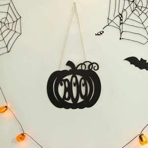 Halloween black BOO pumpkin metal door sign hanging on a wall with festive decorations