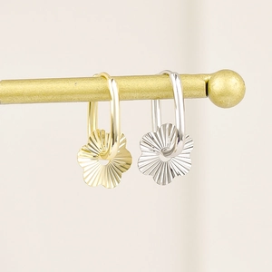 Floral-shaped oval earrings in gold and silver finish hanging on a golden metal bar