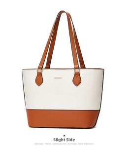 Side view of bicolor tote bag in cream and tan Saffiano leather with metal logo detail