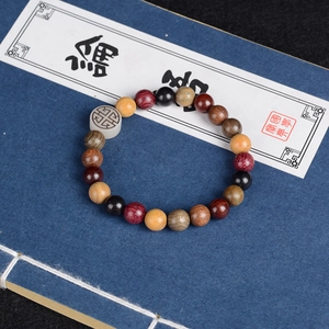 Close-up of multicolored wooden bead bracelet with engraved symbol on old blue book