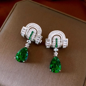 Detailed shot of silver drop earrings with emerald-cut green gems and zircon inlay