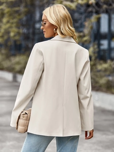Back view of a chic beige short sleeve blazer for women in an urban outdoor setting