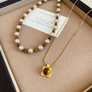 Detailed view of tiger eye stone pendant and pearl necklace set on jewelry display card