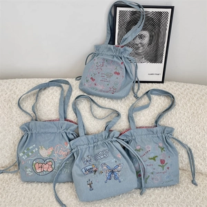 Detailed row of four light blue denim drawstring tote bags with cute embroidery