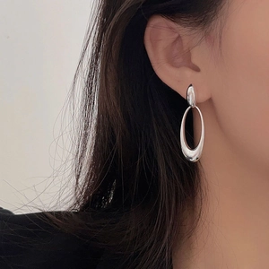 Close-up of minimalist S925 sterling silver oval drop earrings on a female model