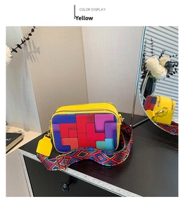 Detail of multi-color geometric patchwork on yellow shoulder bag with wide woven strap