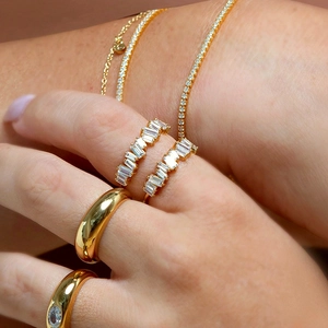 Golden rings and bracelets set featuring rectangular zircon stones on a model's hand
