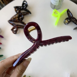 Detail of dark red resin hair claw clip with spring texture and ergonomic hanger shape