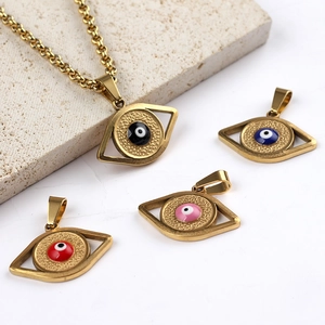Golden Turkish Evil Eye pendants in blue, black, red and pink on a stone display