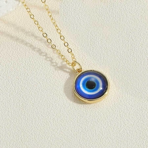 Macro shot of evil eye pendant with blue glass inlay on a gold chain necklace
