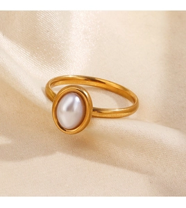 Macro detail of a gold geometric ring featuring an oval pearl on elegant silk fabric