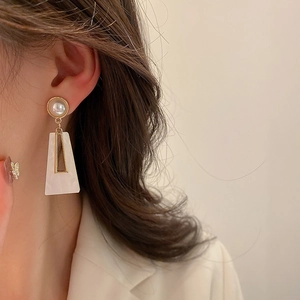 Detail of geometric acrylic trapezoid earring with faux pearl on female model
