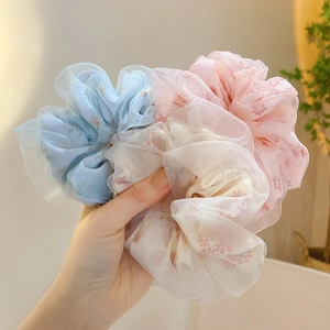 Detailed view of floral chiffon scrunchies in blue, white, and pink sheer fabric