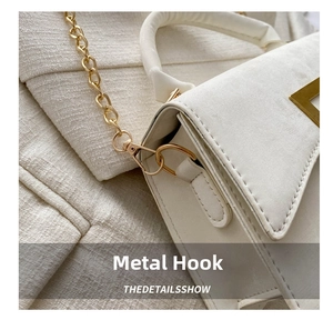 Detail view of gold metal hook and fine chain on white frosted textured leather bag