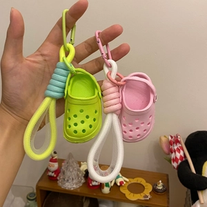 Detail of neon green and pink mini clog keychains with woven lanyards held by hand