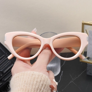 Detail of nude pink cat-eye sunglasses with silver metal hinge accents and tinted lenses