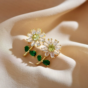 Gold-plated green flower stud earrings with sparkling crystals on beige silk