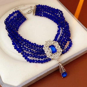 Close-up of vintage multilayer blue beaded necklace with ornate silver gem pendant