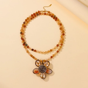 Macro shot of boho multilayer beaded necklace featuring a large amber glass flower pendant