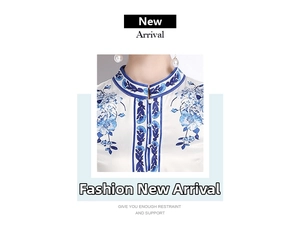 Detail of white satin dress featuring intricate blue floral embroidery and mandarin collar