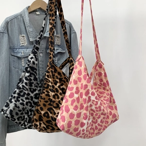 Three leopard print canvas tote bags in brown, grey, and pink hanging on a denim jacket