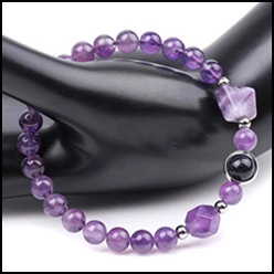 Detail of amethyst beaded bracelet with Hamsa hand charm on a black hand model