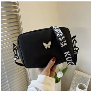 Detail of black nylon crossbody bag with white butterfly and lettered wide strap