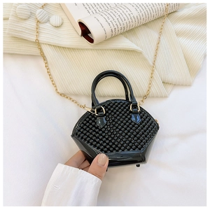 Close-up of black shell-shaped mini bag with rivet texture and gold chain strap