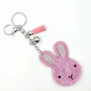 Sparkling crystal rabbit keychain with pink tassels and bell on a minimalist white background