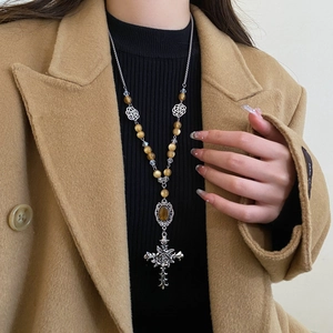 Detailed view of tiger eye beaded necklace with silver rose cross on black sweater