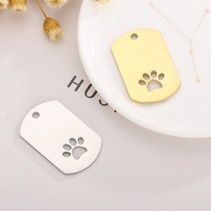 Close-up of gold and silver stainless steel pet tags with hollow paw print detail