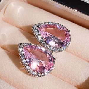 Macro shot of pear-shaped pink zircon earrings with halo diamond setting on velvet