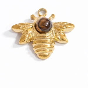 Detail of a gold bee pendant with a brown tiger eye stone and top hanging ring