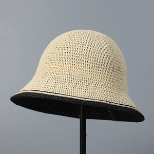 Detailed close-up of woven paper straw bucket hat with beige crown and black brim