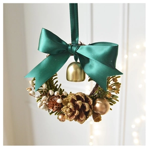 Christmas wreath detail with green ribbon bow, golden bell, and glittery pine cones