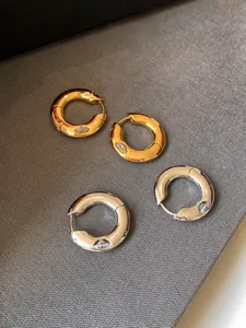 Macro view of gold and silver thick hoop earrings with marquise-cut zircon accents