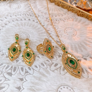 Detail of vintage gold jewelry set with green oval gemstones and lace background