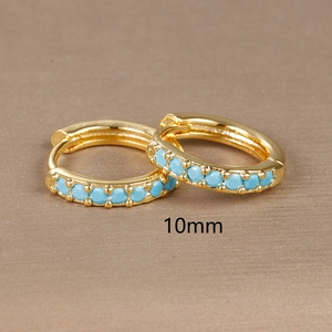 Macro view of 10mm gold hoop earrings set with round blue turquoise stones
