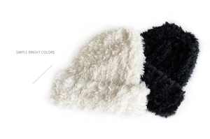 Detail of plush faux fur knitted winter hats in black and white with soft fuzzy textures