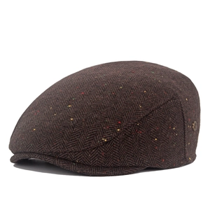 Detailed view of brown herringbone tweed newsboy cap with colorful fiber dots and metal tag