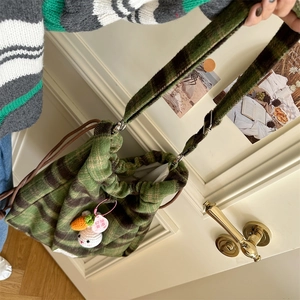 Close-up of green wool bucket bag with drawstring closure and cute crochet rabbit charm