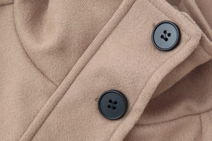 Macro view of camel wool fabric texture and black buttons on the cropped jacket