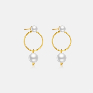 Close-up of elegant gold hoop earrings with white pearls over a reflective surface