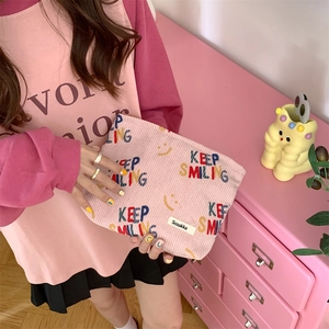 Detailed texture of pink corduroy pouch with KEEP SMILING embroidery and smile logo