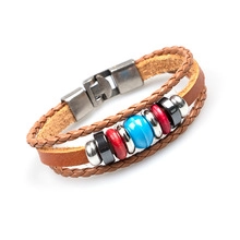 Close-up of multilayer braided brown leather bracelet with colorful ethnic metal beads