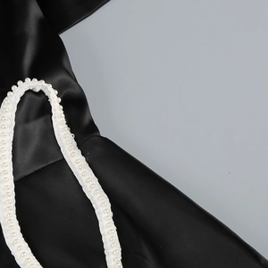 Détail de robe en satin noir avec des perles blanches élégantes sur la bandoulière