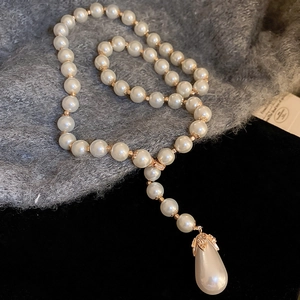 Detailed view of a Y-shaped necklace with round imitation pearls and a teardrop pendant