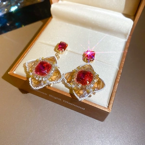 Close-up of vintage flower earrings with red square gems and pearls in a gift box