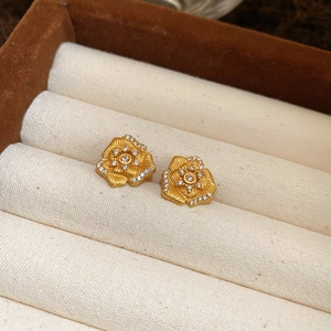 Macro detail of 24K gold plated flower stud earrings with sparkling cubic zirconia