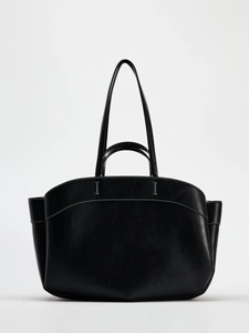 Detail of black leather tote bag featuring white contrast stitching and dual handle design